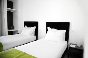2 camas en una habitación con sábanas y almohadas blancas en Benavente Vila Hotel, en Benavente