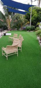 3 Bänke auf einem Rasen mit grünem Gras in der Unterkunft Nu Melati Hotel in Pantai Cenang