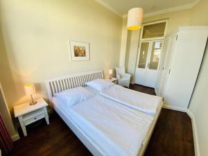 een slaapkamer met een groot wit bed met 2 lampen bij Villa Seevogel/Kormoran in Warnemünde