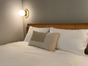 a white bed with a pillow and a light on the wall at GIVE Kagurazaka in Tokyo