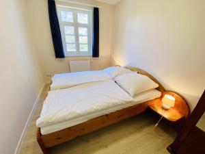 ein Bett mit einem Holzrahmen in einem Zimmer mit einem Fenster in der Unterkunft Wald & Meer/Kapitänsdeck in Warnemünde