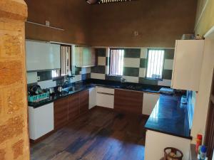 a large kitchen with black and white counters and windows at Chithira Homestay (Kerala traditional mud house) in Kodali