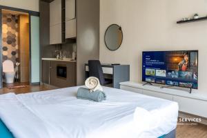 a bedroom with a white bed and a flat screen tv at CeylonZ Suites by Plush in Kuala Lumpur
