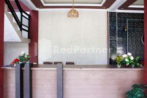 a red pandemic sign on a wall in a lobby with flowers at Hotel Baby Angel Dieng Mitra RedDoorz in Garung