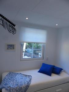 1 cama con almohadas azules en una habitación con ventana en Mini-villa 200 m from Kampinge beach, en Höllviken