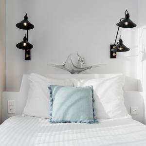 a white bed with white pillows and a blue pillow at Hôtel Le Grand Barnum in Francheville