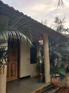 a house with a door and a palm tree at Kenchas Beach Resort in Gokarna