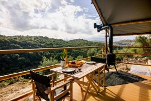 una mesa y sillas en un balcón con vistas en Civara Chalet - Private Glamping in nature with Jakuzzi en Tsivarás