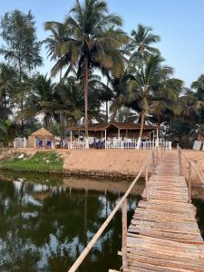a wooden bridge over a body of water with palm trees at The Goko Social in Gokarna