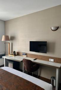 Habitación de hotel con escritorio y TV en la pared. en Kanyonvadi Hotel en Karabuk