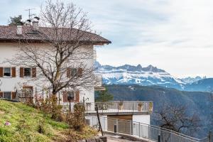 a house on a hill with mountains in the background at Reiterhof Apt Gaia in San Genesio Atesino