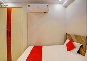 Un pequeño dormitorio con una cama blanca con una manta roja en Hotel Indiana Palace, en Kānpur