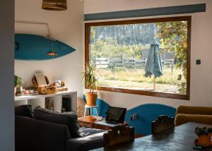 a living room with a window and a laptop on a table at Maceda Surf Camp in Maceda