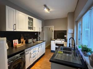 a kitchen with white cabinets and a sink at Tudor House in Leicester