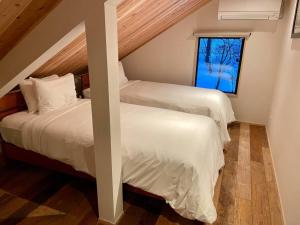 two beds in a room with a window at The Misorano Cottage in Hakuba