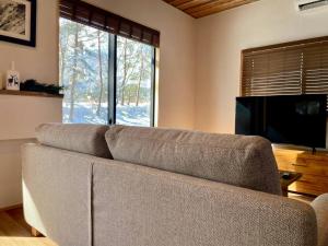 a couch in a living room with a television at The Misorano Cottage in Hakuba