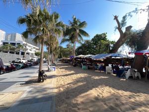 una playa con palmeras, mesas y sombrillas en Pattaya Pool Villa 39B 300 mater to beach gate en Pattaya South