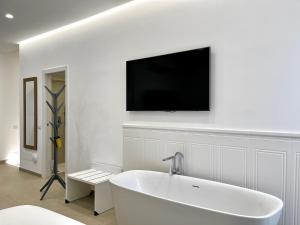 a white bathroom with a tub and a tv on the wall at TRASTEVERE URBAN SUITE in Rome