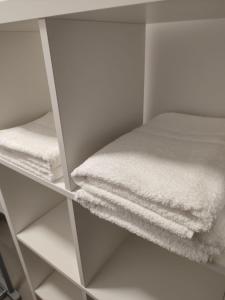 armadio con asciugamani bianchi su una mensola di Camera de familie a Vatra Dornei