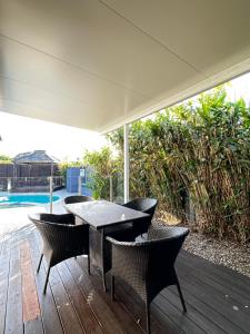 a patio with a table and chairs on a deck at Tranquil Scape-Villa with Pool by Gold Coast Premium in Gold Coast