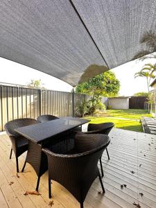 a black table and chairs on a deck with an umbrella at Tranquil Scape-Villa with Pool by Gold Coast Premium in Gold Coast