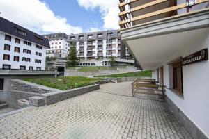 a building with a bench in a courtyard with buildings at Studio Genzianella Ski In-Ski Out Mt 100 - Happy Rentals in Sestriere