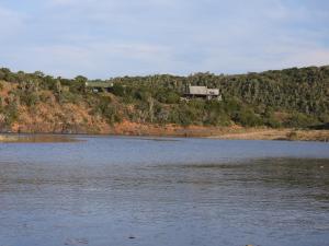 une maison sur une colline à côté d'une masse d'eau dans l'établissement African Safari Lodge, à Grahamstown