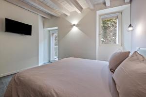 um quarto branco com uma cama e uma televisão em La Casa Incartata - Carta Velina em Toscolano Maderno
