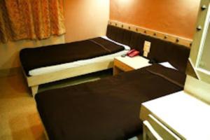 Hotel Monsoon , Shillong في شيلونغ: غرفة صغيرة بسريرين وطاولة