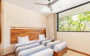 twee bedden in een kamer met een groot raam bij Private pool and rooftop in Aldea Zama, 24 7 security in a gated community 15 in Tulum