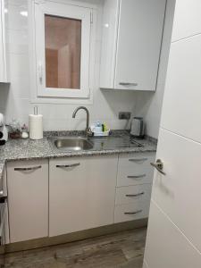 une cuisine avec des armoires blanches et un évier dans l'établissement Apartament dels Mestres, à Móra d'Ebre