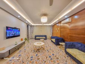 - un hall avec une salle d'attente dotée d'un mobilier bleu et d'une télévision dans l'établissement Pratishtha 4BHK, DLF Phase 1, Gurgaon, à Gurgaon