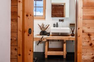 a bathroom with a sink and a wooden table at Chalet Marmo by HomeFlow in Zermatt