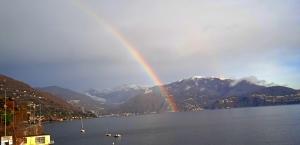 a rainbow in the middle of a lake with mountains at Trattoria Della Cascata B&B in Oggebbio