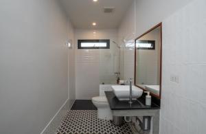 W łazience znajduje się toaleta, umywalka i lustro. w obiekcie Ploen Pirom w Lat Krabang