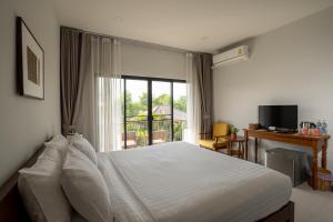 a bedroom with a white bed and a window at Ploen Pirom in Lat Krabang