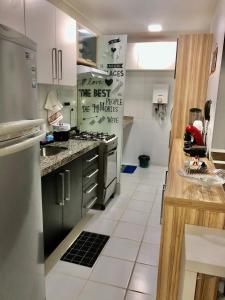 uma cozinha com armários pretos e piso em azulejo branco em Apartamentos Praia de Pajucara em Maceió