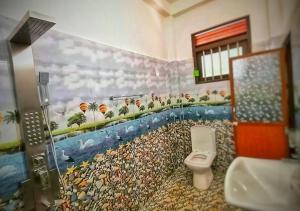 a bathroom with a toilet and a painting on the wall at Moon End Villa in Hikkaduwa +8 photos