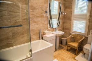 a bathroom with a tub and a toilet and a sink at Cambridge Villa in Warwick