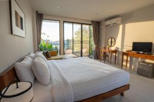 a bedroom with a large white bed and a balcony at Ploen Pirom in Lat Krabang