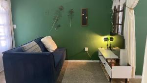 a living room with a blue couch and a green wall at ACM Flat in Natal