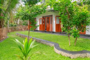 Sun See Villa Hikkaduwa في هيكادوا: منزل بأبواب برتقالية وأشجار في ساحة