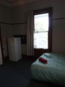 um quarto com uma cama, uma janela e um frigorífico em Ballymena House em Dunedin
