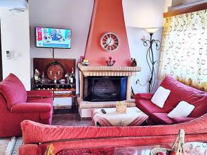 uma sala de estar com mobiliário vermelho e uma lareira em VILLA EFTYXIA - Mendenitsa em Mendhenítsa