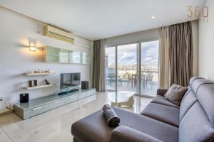 sala de estar con sofá y TV en Beautiful seafront home with private balcony & BBQ by 360 Estates en Pietà