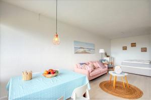 een woonkamer met een tafel en een roze bank bij Ferienpark - Haus L, App 0L0610 in Heiligenhafen