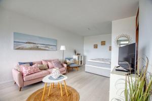 een woonkamer met een roze bank en een bed bij Ferienpark - Haus L, App 0L0610 in Heiligenhafen