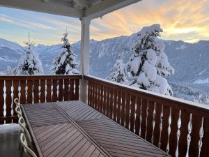 a porch with a view of snow covered trees and mountains at Charmant appartement au Vagabond in Leysin