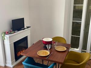 a dining room table with a fireplace and a television at Charmant appartement au Vagabond in Leysin