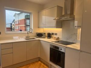 uma cozinha com armários brancos, um lavatório e uma janela em New build 1 bedroom modern apartment Rickmansworth em Rickmansworth